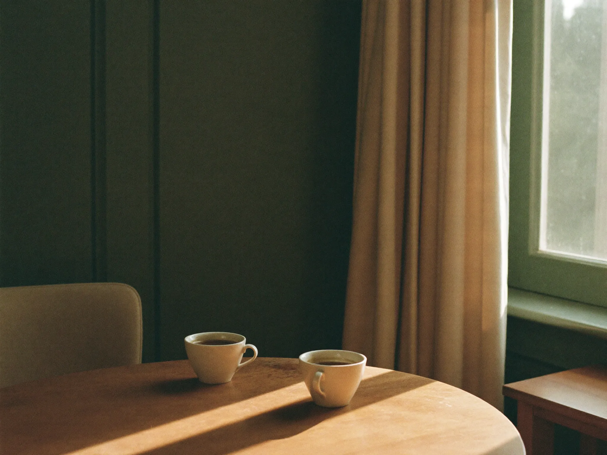 Twee kopjes koffie op een houten tafel in warm licht, klaar voor een kennismaking