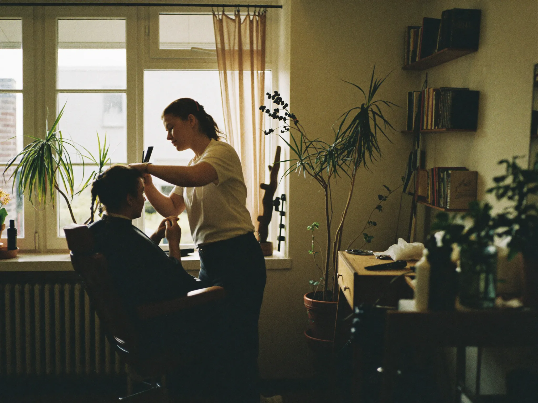 Kapper aan het werk in een kleine salon met warm daglicht